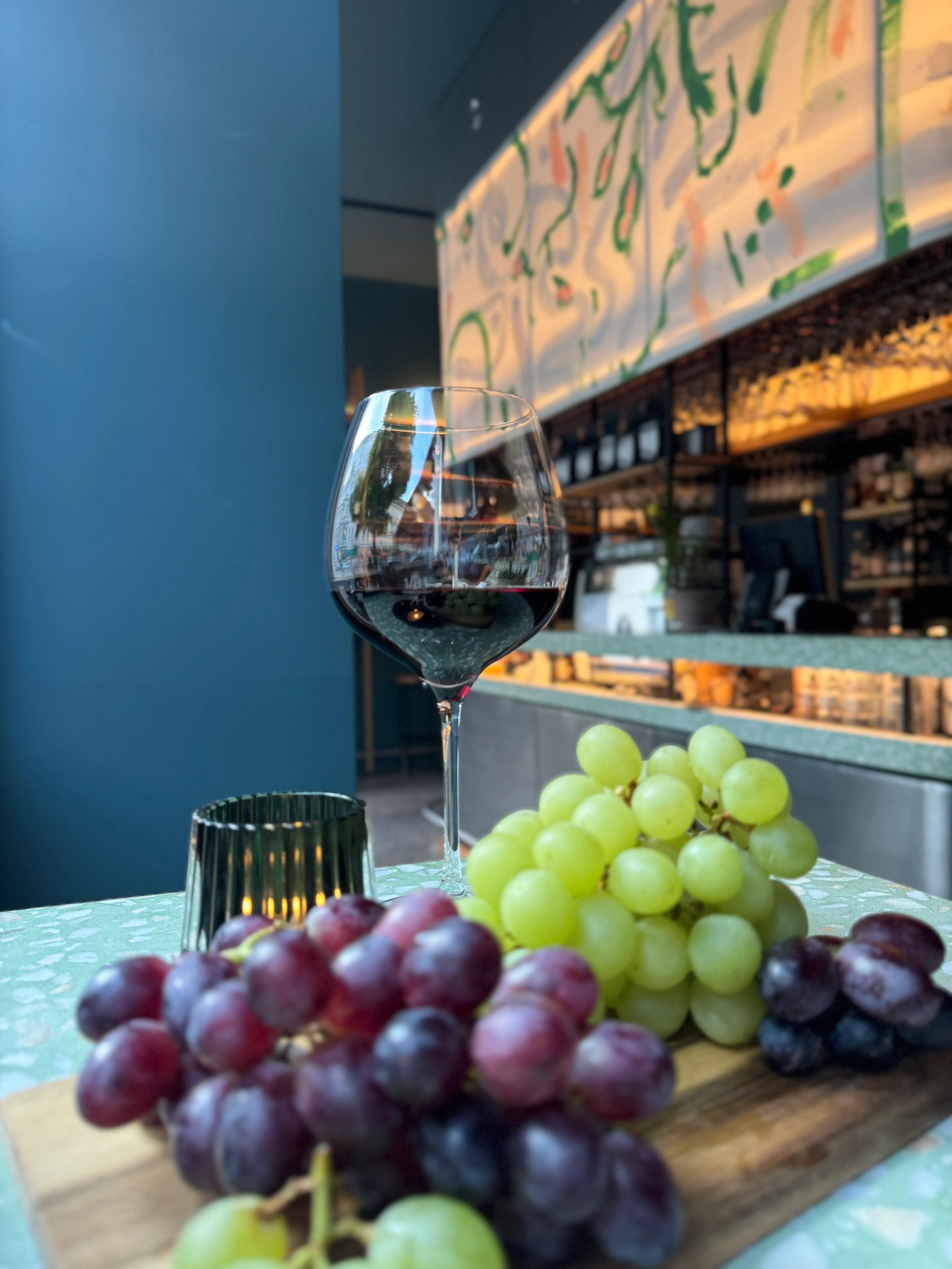 Rotwein und Trauben auf einem Holzteller in einer Bar